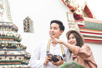 Fototapeta na wymiar Asian couple tourists visiting ancient Thai temple