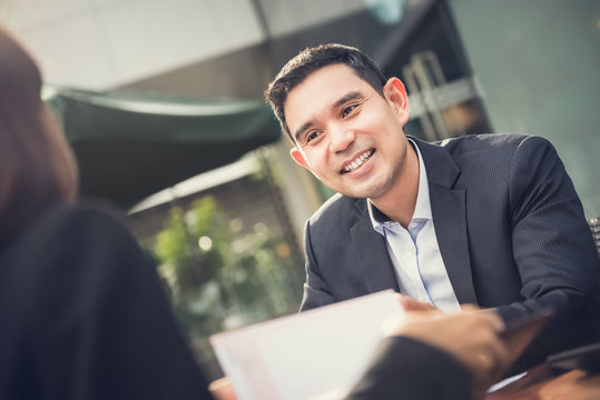 Smiling Asian Businessman Meeting With Client In Cafe