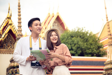 Fototapeta premium Asian couple tourists visiting Thai temple, Wat Pho, in Bangkok Thailand