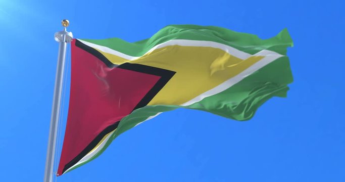 Flag of Guyana waving at wind in slow in blue sky, loop