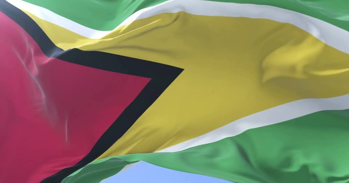 Guyana flag waving at wind in slow in blue sky, loop