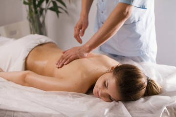 Fototapeta na wymiar Blonde young woman model receiving relaxing massage in spa room
