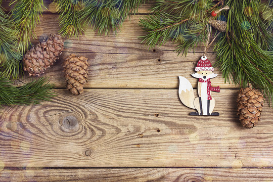 Christmas background with decorative fox and pine branches on old wooden boards with space for text.