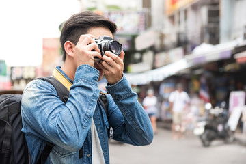 Traveling Asian male tourist backpackers taking photo in Khao san road,  Bangkok, Thailand