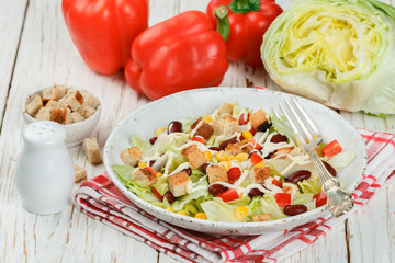 Delicious salad of iceberg lettuce with red beans, bell pepper, corn, cheese and croutons. Selective focus