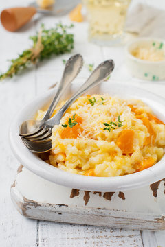 Pumpkin risotto with thyme, garlic, parmesan cheese and white wine on light wooden background. Selective focus. Rustic style. Top view.