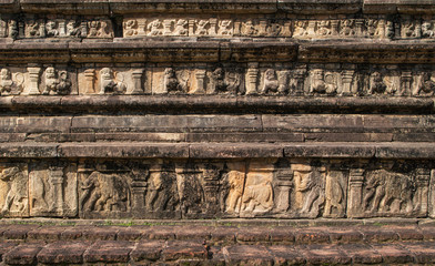 Fragment of a wall of an ancient palace or temple with the bas-relief representing rows of elephants, lions and mythical people. A mystical background for storytelling in a genre of 'lost'. 