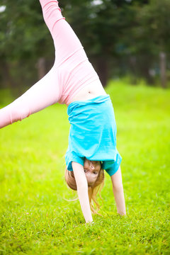 Active little school girl somersault outdoors.