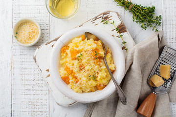 Pumpkin risotto with thyme, garlic, parmesan cheese and white wine on light wooden background. Selective focus. Rustic style. Top view.