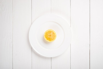 Fresh lemon in a plate on wooden background. Half of lemon