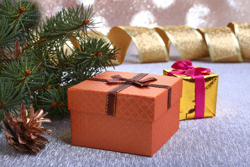 Christmas decoration with gift boxes, christmas tree and cones on a blurry, sparkling and fabulous background.