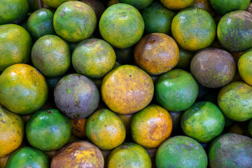 Pile of natural organic local thai tangerine orange fruit background in yellow, green color and marked skin texture selling in market