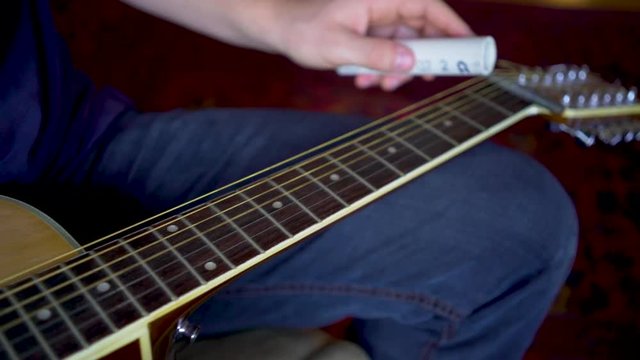 Very closeup on slider on the strings of the six string slide guitar.
