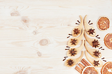 Christmas tree of spoons and anise stars, clove, cinnamon sticks, oranges on white wood background.