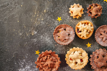 Different sizes of traditional Christmas dessert - Mince pies. Vanilla and chocolate pastry. Black backdrop.Top view.