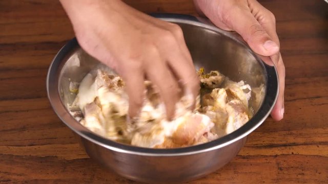 Lady Mixing Chicken and other marinating ingredients together in a bowl - Closeup Shot 