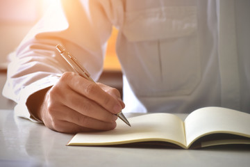 Close up hand writing in an agenda on a desk at home or office