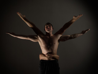 Obraz premium Young sports couple doing acroyoga exercises in a dark room