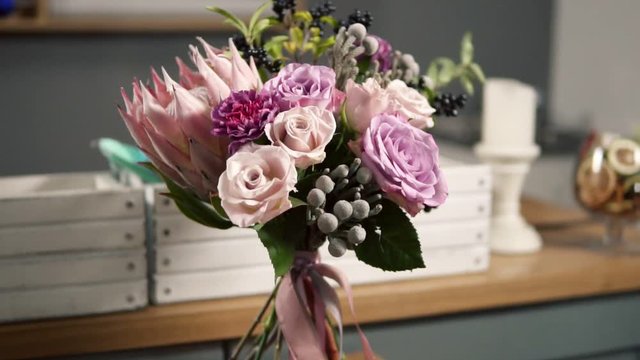 Camera round movement: beautiful fresh bouquet in the flower shop: floral composition consists of Rose, Brunia, Protea with beautiful ribbon