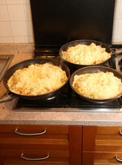 three big pans with the food named frico a typical italian dish
