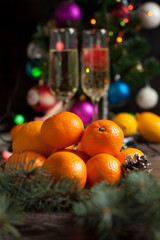 Fototapeta na wymiar traditional New Year's table, tangerines, champagne, Christmas tree and New Year's lights