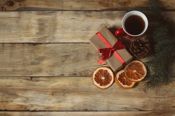 Cup of tea, a gift, a dried grapefruit and a spruce cone on a wooden background. Top view, flat lay