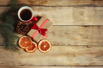 Obraz na płótnie Canvas Cup of tea, a gift, a dried grapefruit and a spruce cone, spruce branches on a wooden background. Top view
