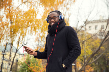 African American male in headphones. A young man listens to music on his smart phone.