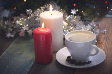 Obraz na płótnie Canvas A romantic festive still life with burning candles and a cup of freshly brewed coffee. Dark Christmas background. Blurred bokeh