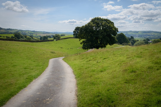 asphalt road leading into the green and hilly countryside England