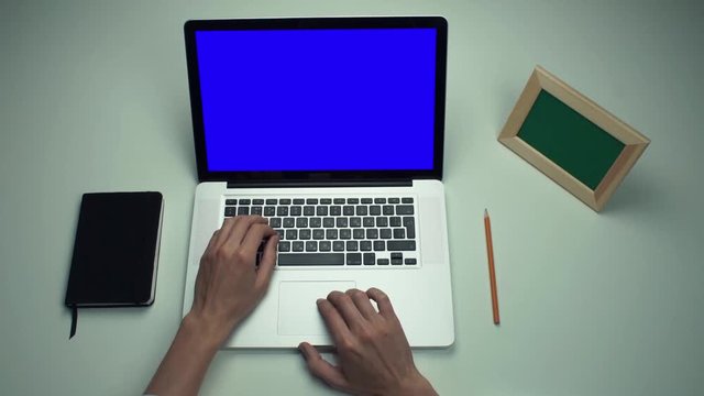 Freelancer using laptop computer with green screen at white desk