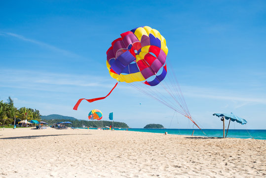  Beach recreation. Colorful parasail on tropical beach clear blue sky,travel destination.