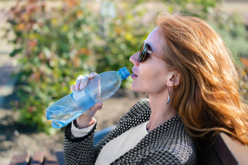 the red-haired girl in sunglasses with water bottle