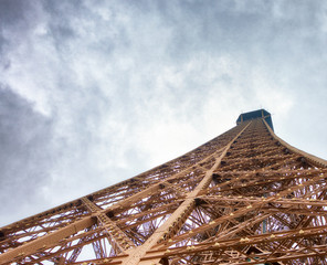 Fototapeta na wymiar Eiffel Tower top structure, skyward view on a cloudy day - Paris, France
