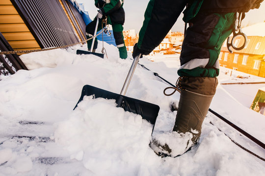 Cleaning roofs of buildings from snow, ice in the winter with a shovel.