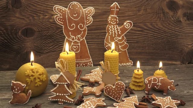 Christmas homemade gingerbread cookies on wooden desk. Yellow scented candles made from natural beeswax.
