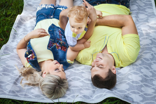beautiful young family resting in city park, cute couple playing with his little baby, concept happy family