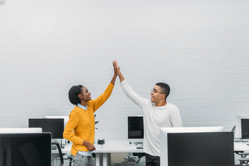 young african american business partners giving high five at office