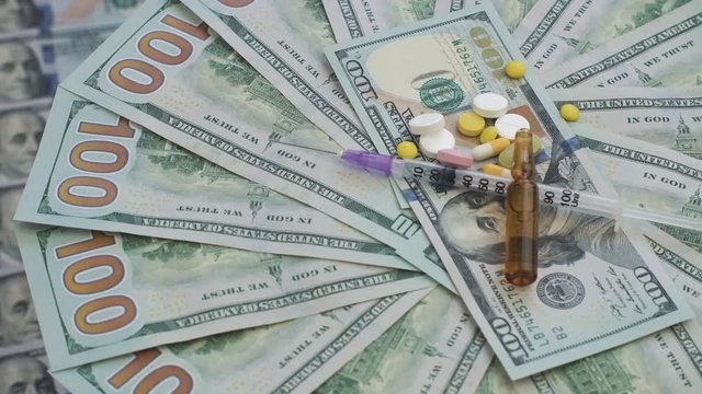 Drugs and pills for addiction lie on the thousands of paper dollars. The frame rotates counterclockwise.