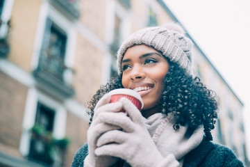 Young black woman drinking coffee wandering in the streets of Madrid on winter