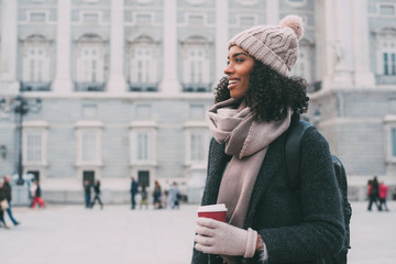 .Young black woman drinking coffee wandering in the streets of Madrid on winter
