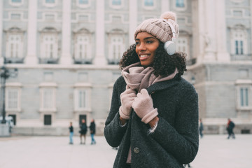 Young black woman listening to music and dancing on the mobile phone near the royal palace in winter  . - Powered by Adobe