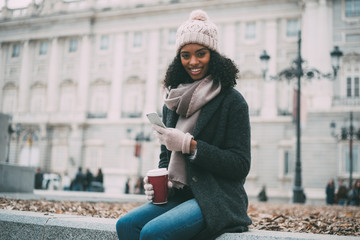 Fototapeta premium Young black woman on the mobile phone near the royal palace in winter .