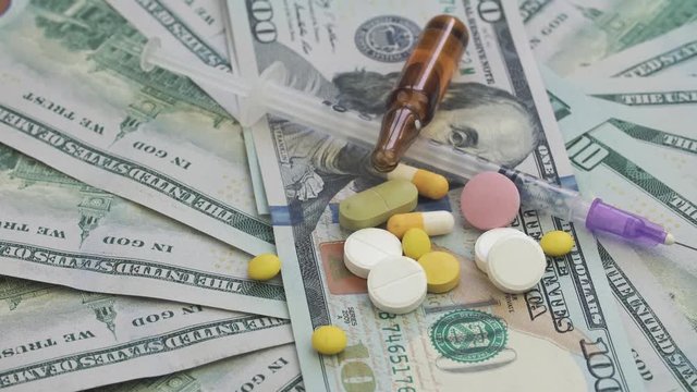 Drugs and pills for addiction lie on the thousands of paper dollars. The frame rotates counterclockwise.
