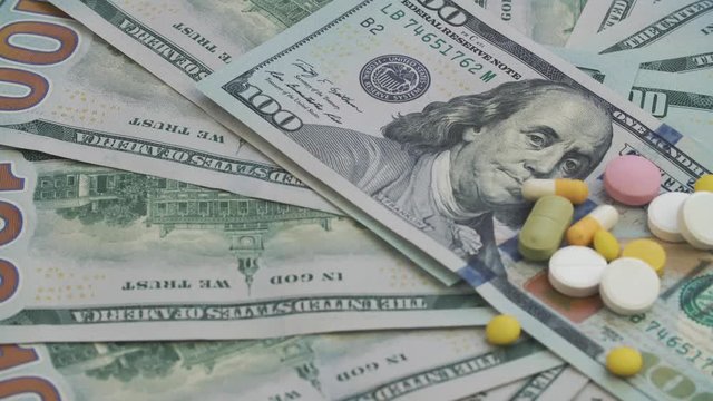 Drugs and pills for addiction lie on the thousands of paper dollars. The frame rotates counterclockwise.