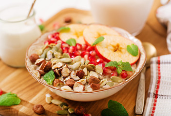 Tasty and healthy oatmeal porridge with apples, pomegranate and nuts. Healthy breakfast. Fitness food. Proper nutrition