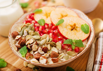 Tasty and healthy oatmeal porridge with apples, pomegranate and nuts. Healthy breakfast. Fitness food. Proper nutrition
