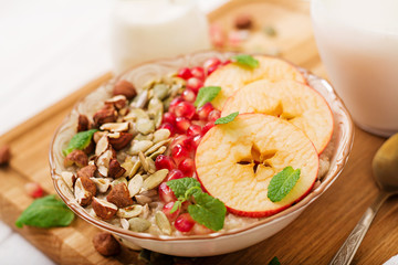 Tasty and healthy oatmeal porridge with apples, pomegranate and nuts. Healthy breakfast. Fitness food. Proper nutrition