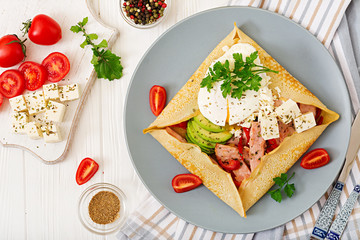 Fototapeta na wymiar French cuisine. Breakfast, lunch, snacks. Pancakes with egg poached, feta cheese, fried ham, avocado and tomatoes on white table. Top view