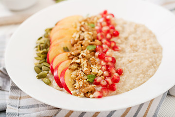 Tasty and healthy oatmeal porridge with apples, pomegranate and nuts. Healthy breakfast. Fitness food. Proper nutrition